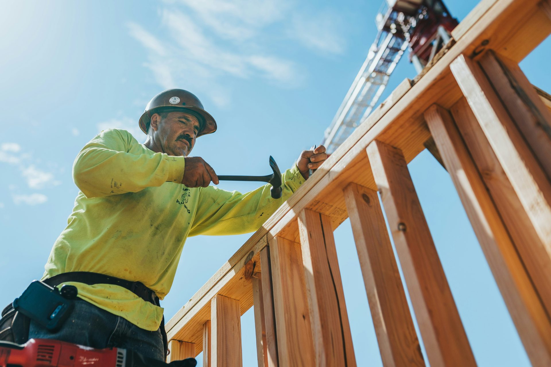 A carpenter in a hard hat and high-visibility shirt framing a timber roof.
